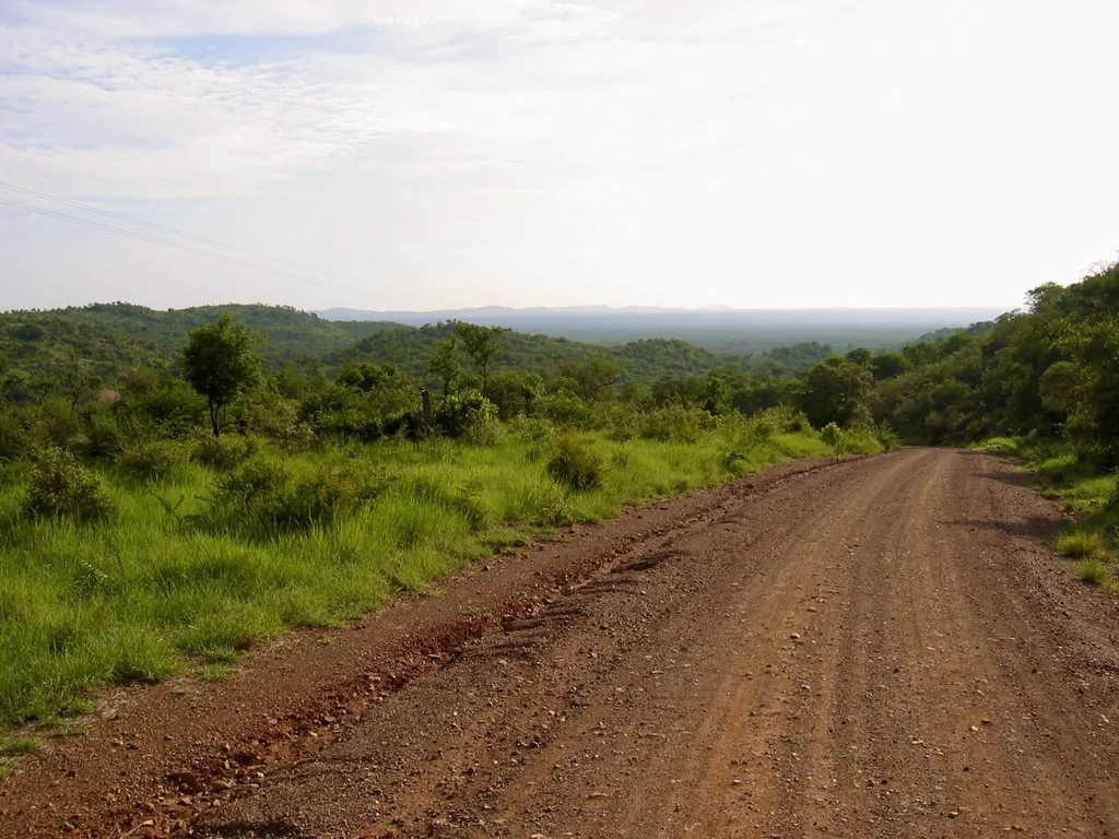 A laterite road cutting through green hills, the kind of unbuilt road this firm is named for.