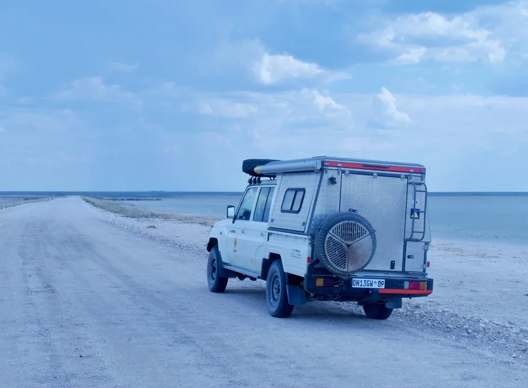 A Land Cruiser parked on a Makgadikgadi salt pan, the horizon vanishing into white.